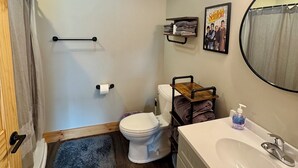 Ein Badezimmer mit Toilette, Waschbecken, Handtuchhalter, Duschvorhang und einem Bild an der Wand.