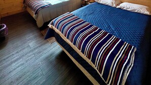 A cabin with two beds, a ceiling fan, a fireball sign, and a window with a view of trees.