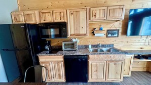 A kitchen with wooden cabinets, a black refrigerator, a microwave, a toaster, and a dishwasher.