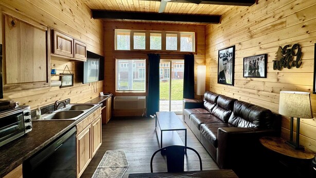 A cabin interior with a kitchen, dining area, and a leather couch.