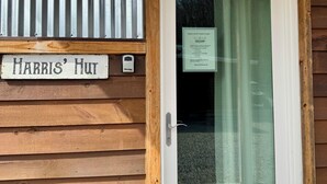 Fachada de madera con pared de metal corrugado, una puerta y un timbre encima.