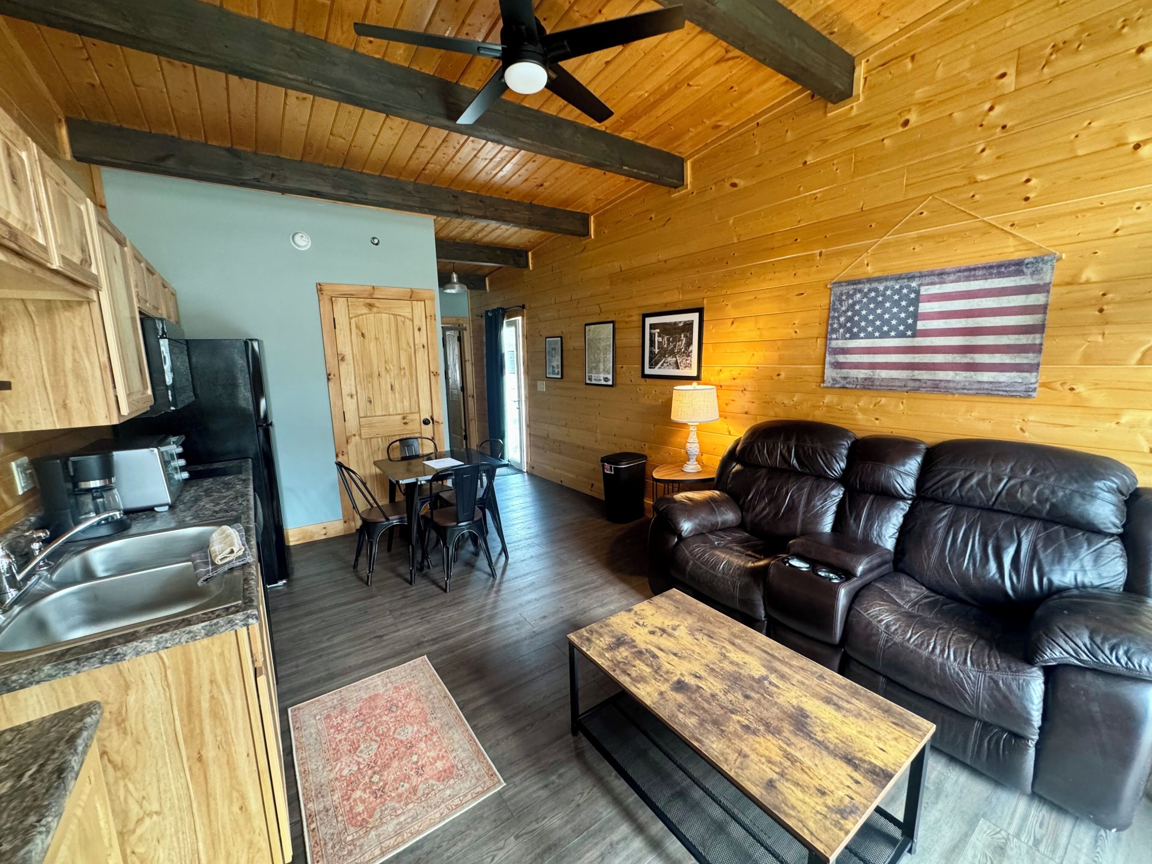 A wooden interior with a dining area, a sofa, and a flag on the wall.