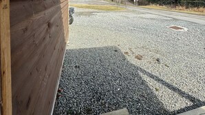 A wooden cabin with a gravel driveway and a sign reading 'W.T'S DIVE'.