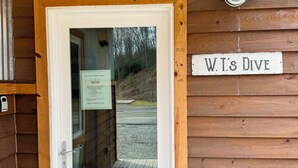A wooden cabin entrance with a door, a welcome sign, and a sign reading 'W.T.'s Dive'.
