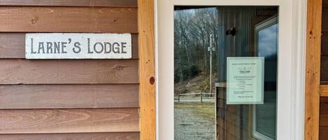 En trædør med et skilt, der siger 'Larne's Lodge', og et velkommenskilt til ATV TrailCamp.
