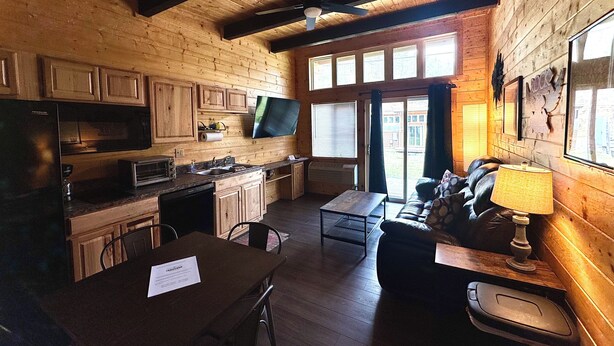 Interior de una cabaña de madera con cocina, comedor y sala de estar.