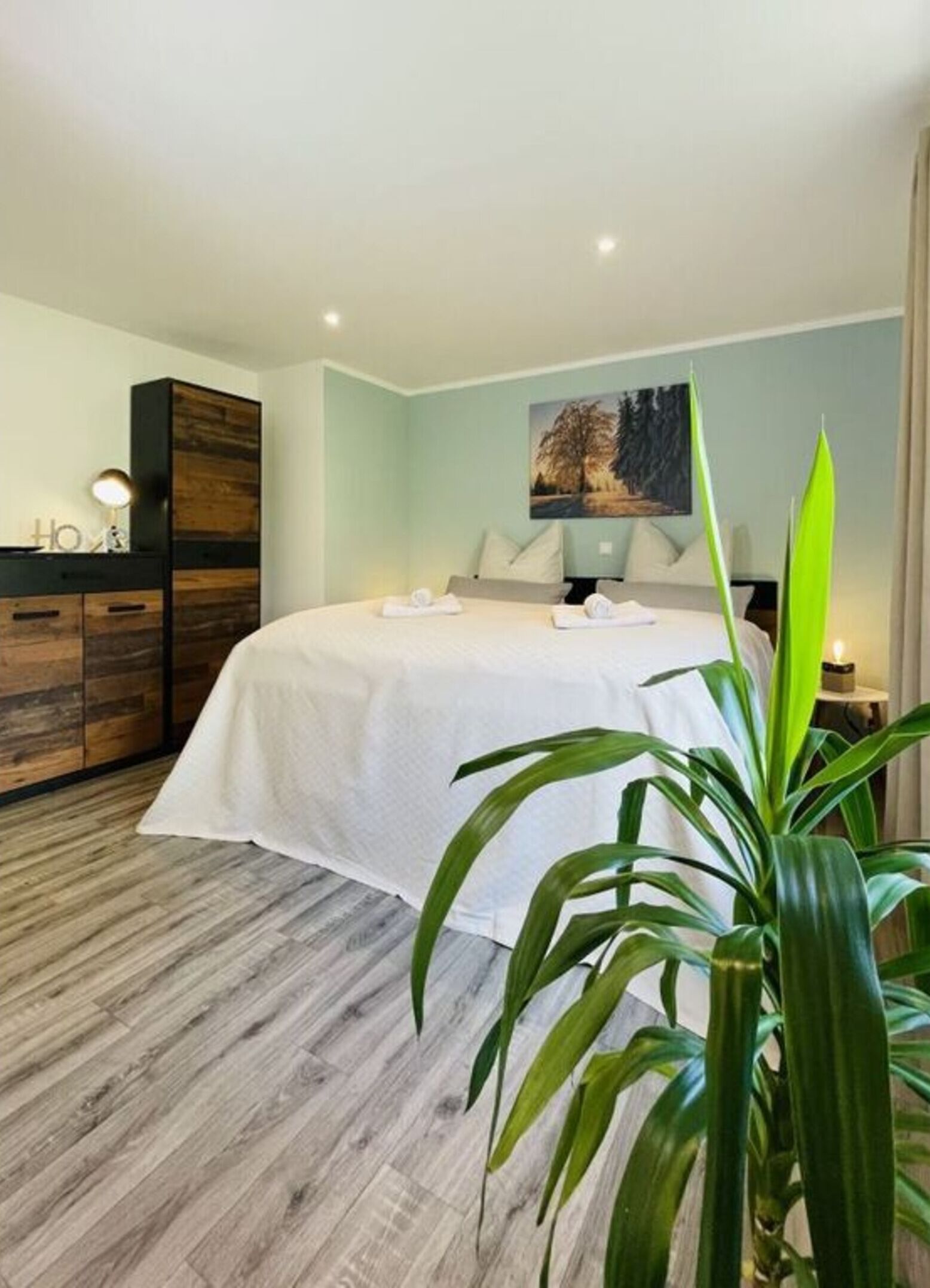 Ein modernes Schlafzimmer mit einem großen Bett, einer hölzernen Kommode und einem Bild an der Wand.