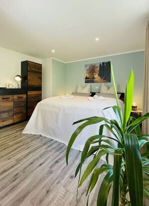 A modern bedroom with a large bed, a wooden dresser, and a painting on the wall. - Holiday Apartment Mountain View (Klingenthal)