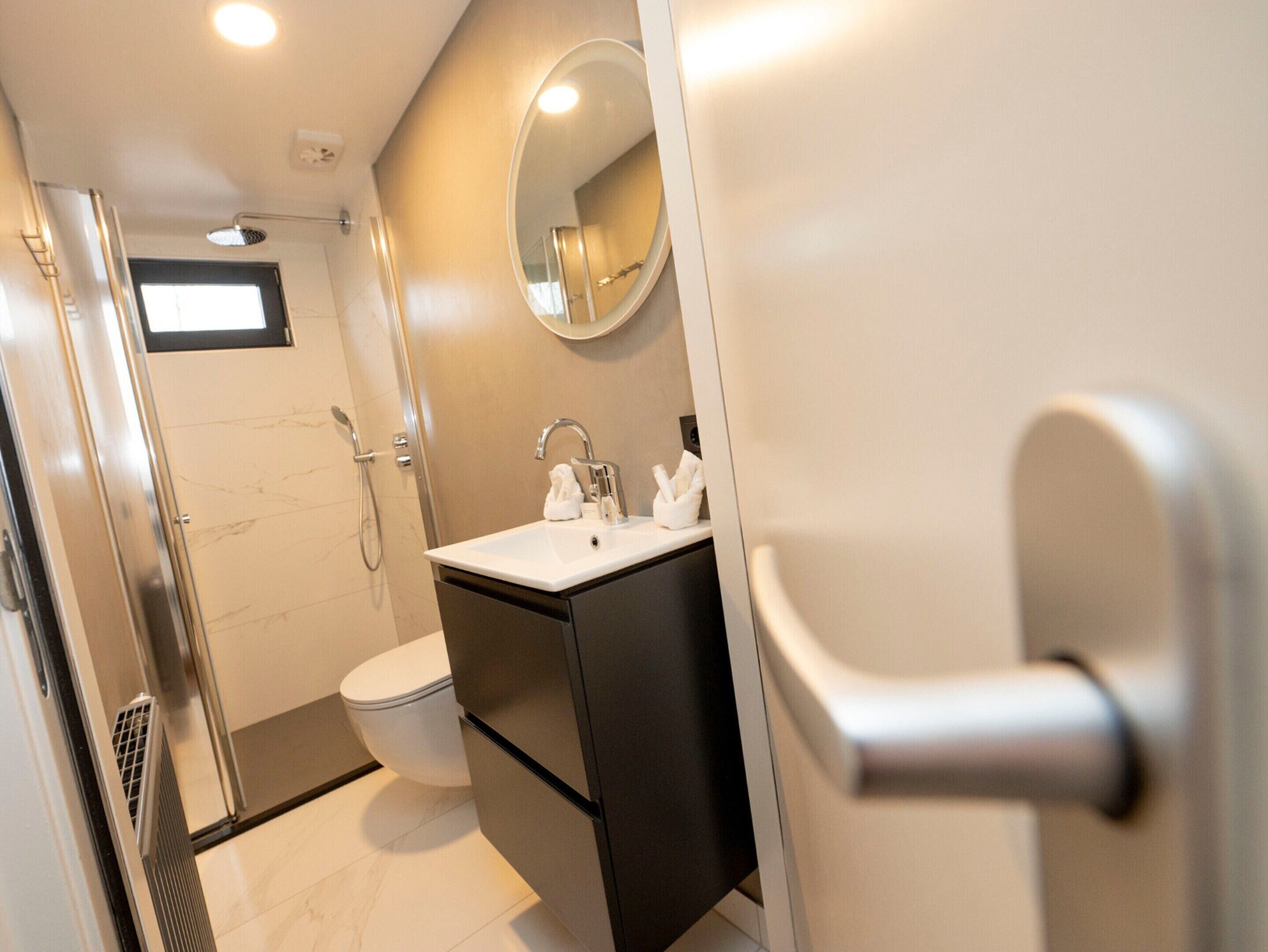 A modern bathroom with a shower, toilet, and sink.