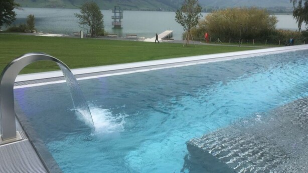 A swimming pool with a view of a lake and mountains in the background. - Farm in the Agerital (Oberaegeri)