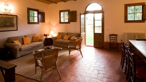 A cozy living room with a fireplace, a sofa set, a dining table with chairs, and a large window with a view of the outdoors. - Spacious Holiday Home in Brisighella (Brisighella)