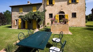 A two-story stone house with yellow shutters, a stone chimney, and a small balcony with potted plants. - Spacious Holiday Home in Brisighella (Brisighella)