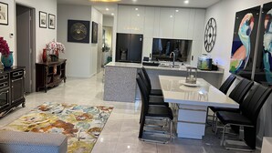 A modern kitchen with a central island, black bar stools, and a chandelier. - Centre of town  (Sydney)