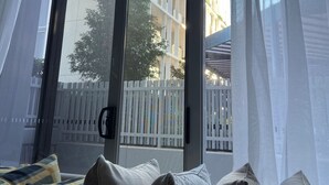 A room with a large window, a view of a building outside, and a sofa with patterned cushions. - Centre of town  (Sydney)