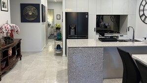 A modern kitchen with a central island, white cabinetry, and a large clock on the wall. - Centre of town  (Sydney)