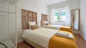 Une chambre d’hôtel avec deux lits, une fenêtre donnant sur un beau paysage, un miroir et un étendoir.