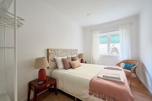 A bedroom with a bed, bedside tables, a chair, a window with curtains, and a view of the outside.
