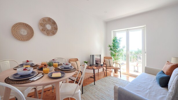 Un coin repas avec une table mise pour le petit-déjeuner, un canapé et un téléviseur.