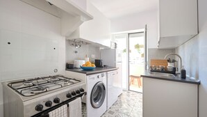 Une cuisine moderne équipée d’une cuisinière à gaz, d’un lave-linge et d’un évier.