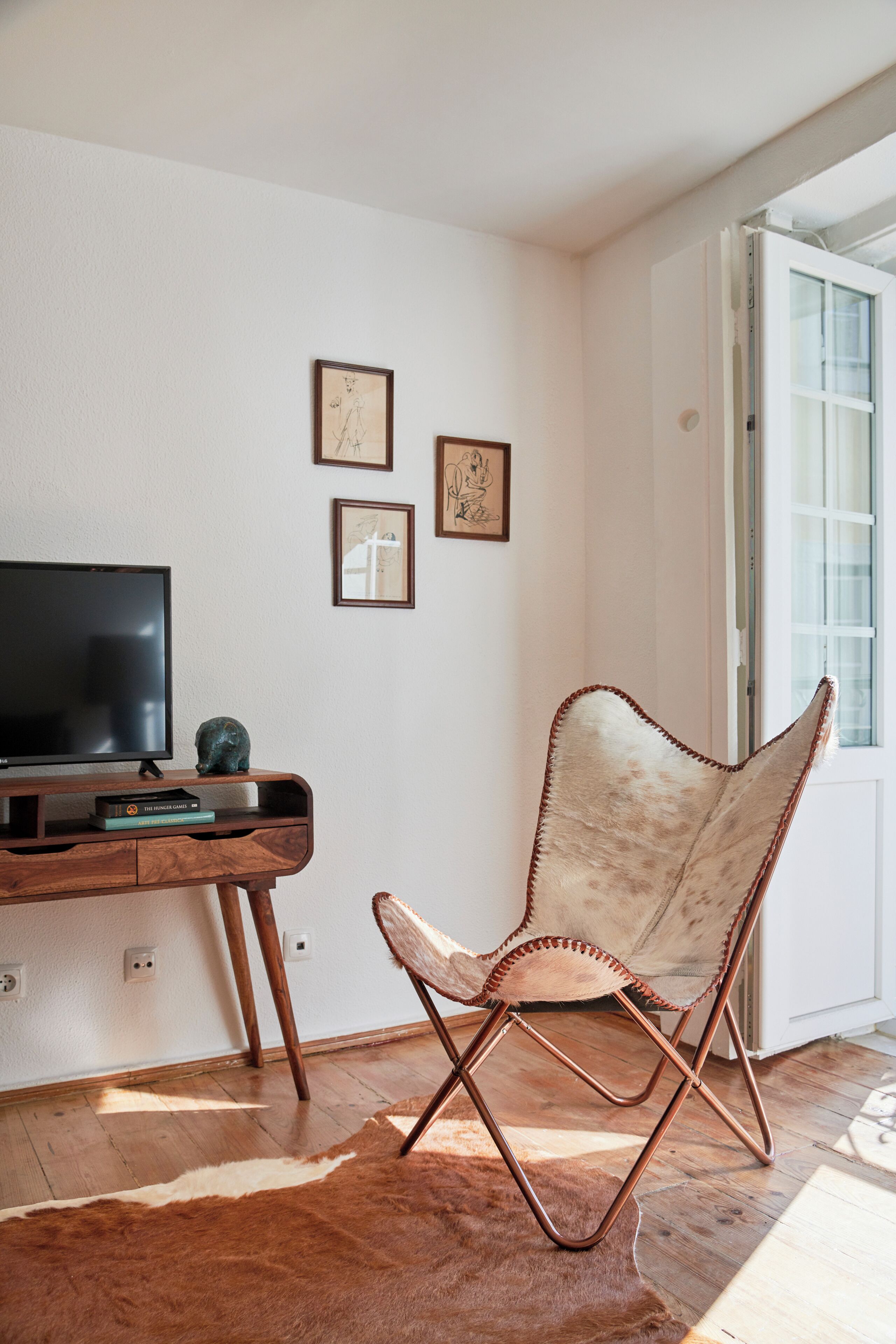 Une pièce comprenant un bureau en bois, un téléviseur, un fauteuil en cuir et des œuvres d’art encadrées accrochées au mur.
