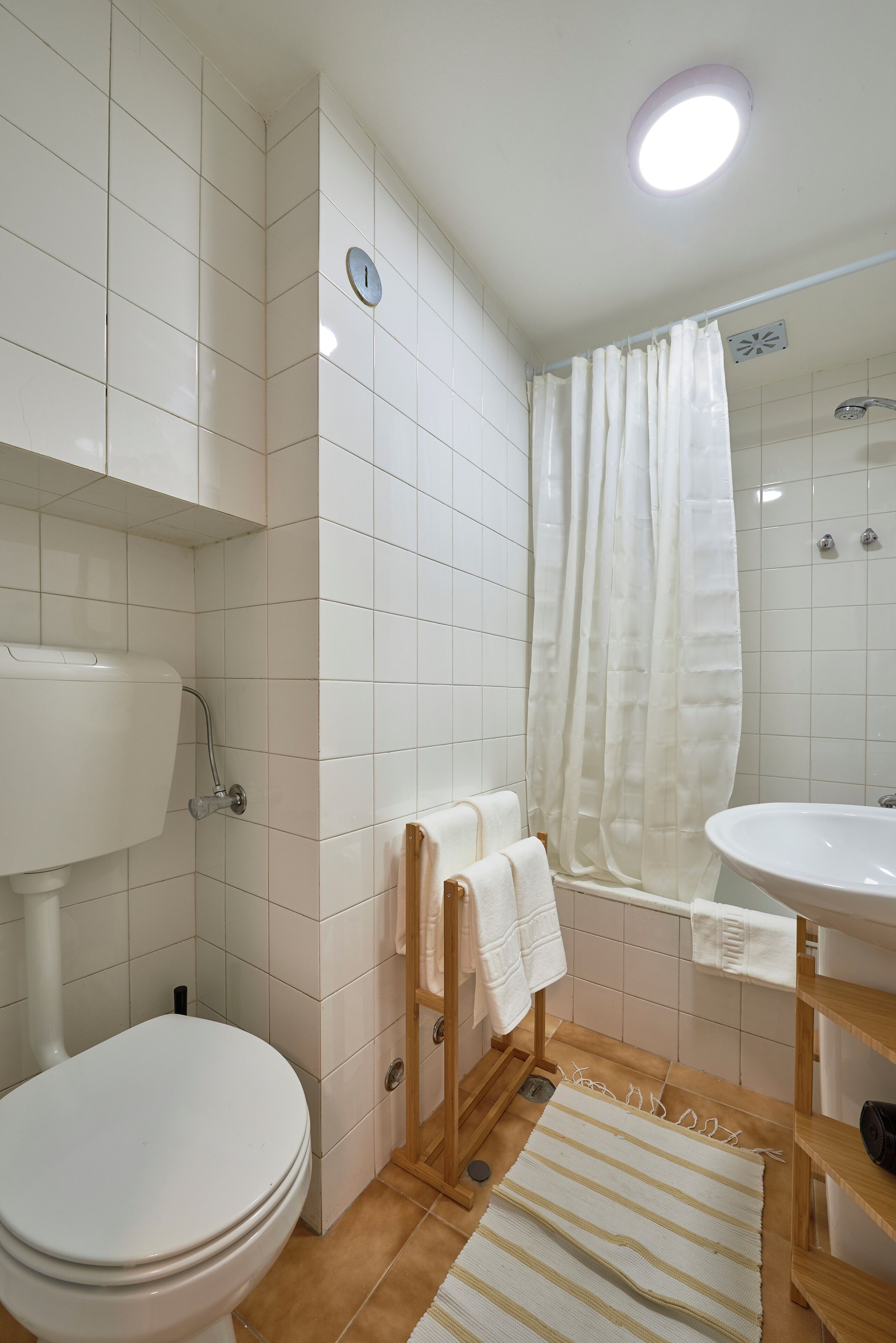 Een badkamer met toilet, wastafel, douche en een betegelde vloer.