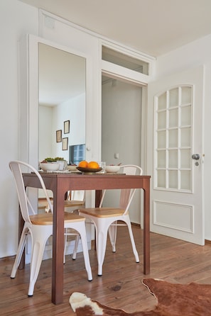 A dining area with a wooden table, white chairs, a mirror, and a door with frosted glass panels.