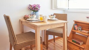 A wooden dining table with chairs, a vase of flowers, a cup, and a book shelf. - Central, Comfy And Light-Filled Apt, By Timecooler (Lisbon)