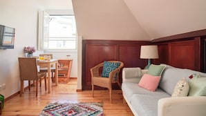 A cozy living room with a wooden dining table, wicker chairs, a sofa with cushions, and a lamp. - Central, Comfy And Light-Filled Apt, By Timecooler (Lisbon)