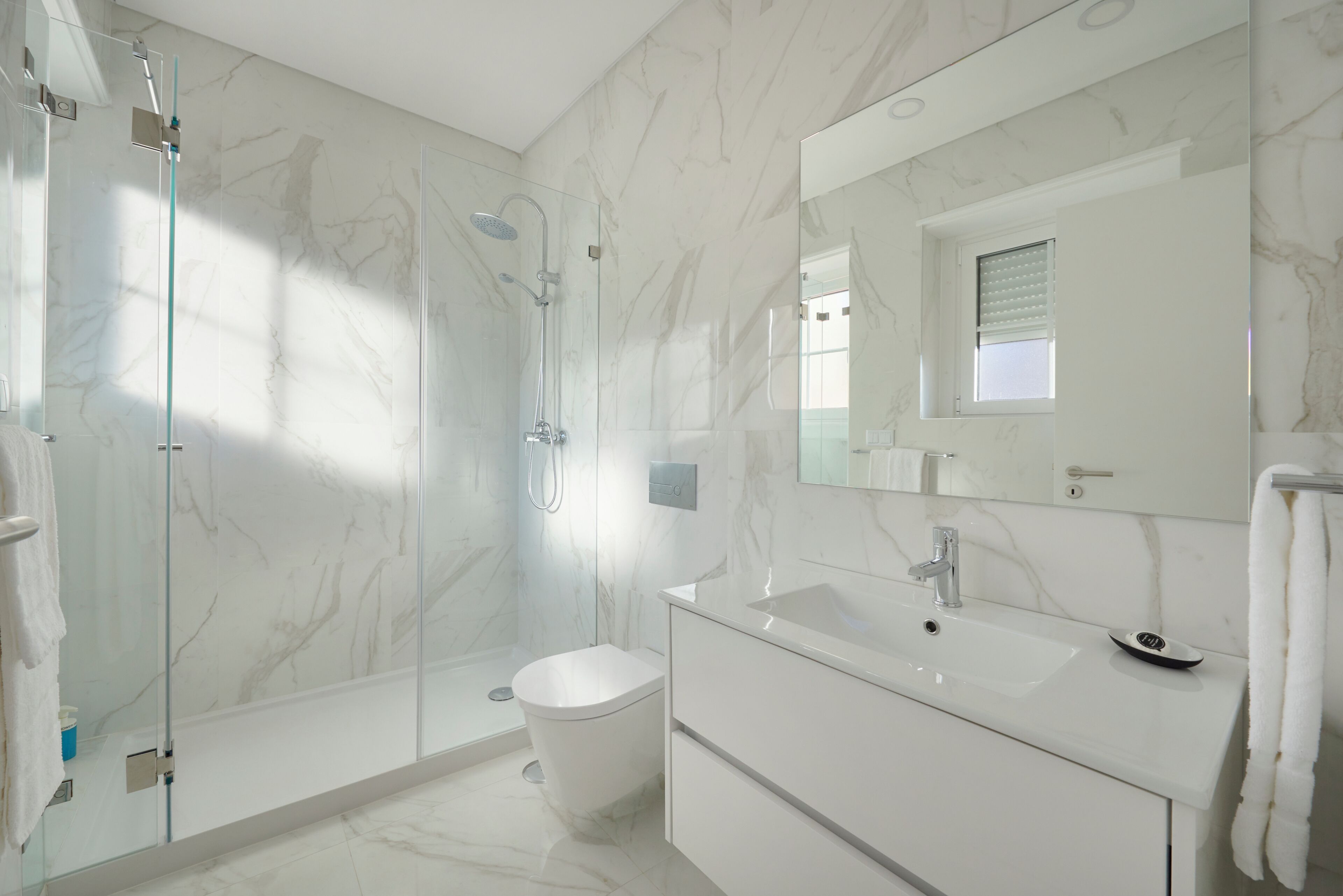 A modern bathroom with a glass-enclosed shower, a white toilet, and a vanity with a sink and mirror.