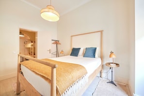 Un dormitorio con una cama de madera, una lámpara de noche y un armario con espejo.