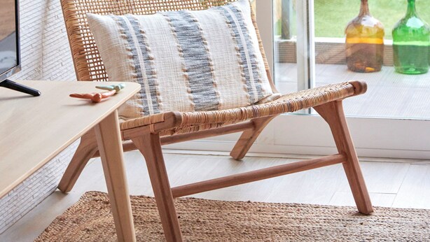 A wicker chair with a cushion, a wooden table, and a large window with a view of a garden and a fence. - Charming And Central Br Apartments, By Timecooler (Lisbon)