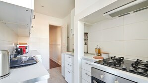 A modern kitchen with white cabinetry, a gas stove, and a kettle. - Charming And Central Br Apartments, By Timecooler (Lisbon)