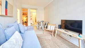 A modern living room with a sofa, TV, and a dining area with chairs and a table. - Charming And Central Br Apartments, By Timecooler (Lisbon)