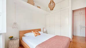 Un dormitorio con cama, mesitas de noche, un armario y una lámpara colgante.