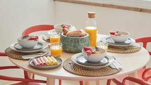 A breakfast table with plates, bowls, and a bottle of orange juice. - Light Filled & Renovated Apartment, By Timecooler (Lisbon)