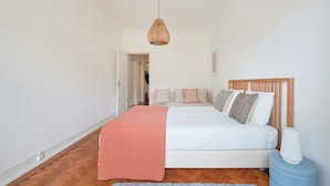 A bedroom with a bed, a hanging light fixture, a bedside table, and a nightstand. - Light Filled & Renovated Apartment, By Timecooler (Lisbon)
