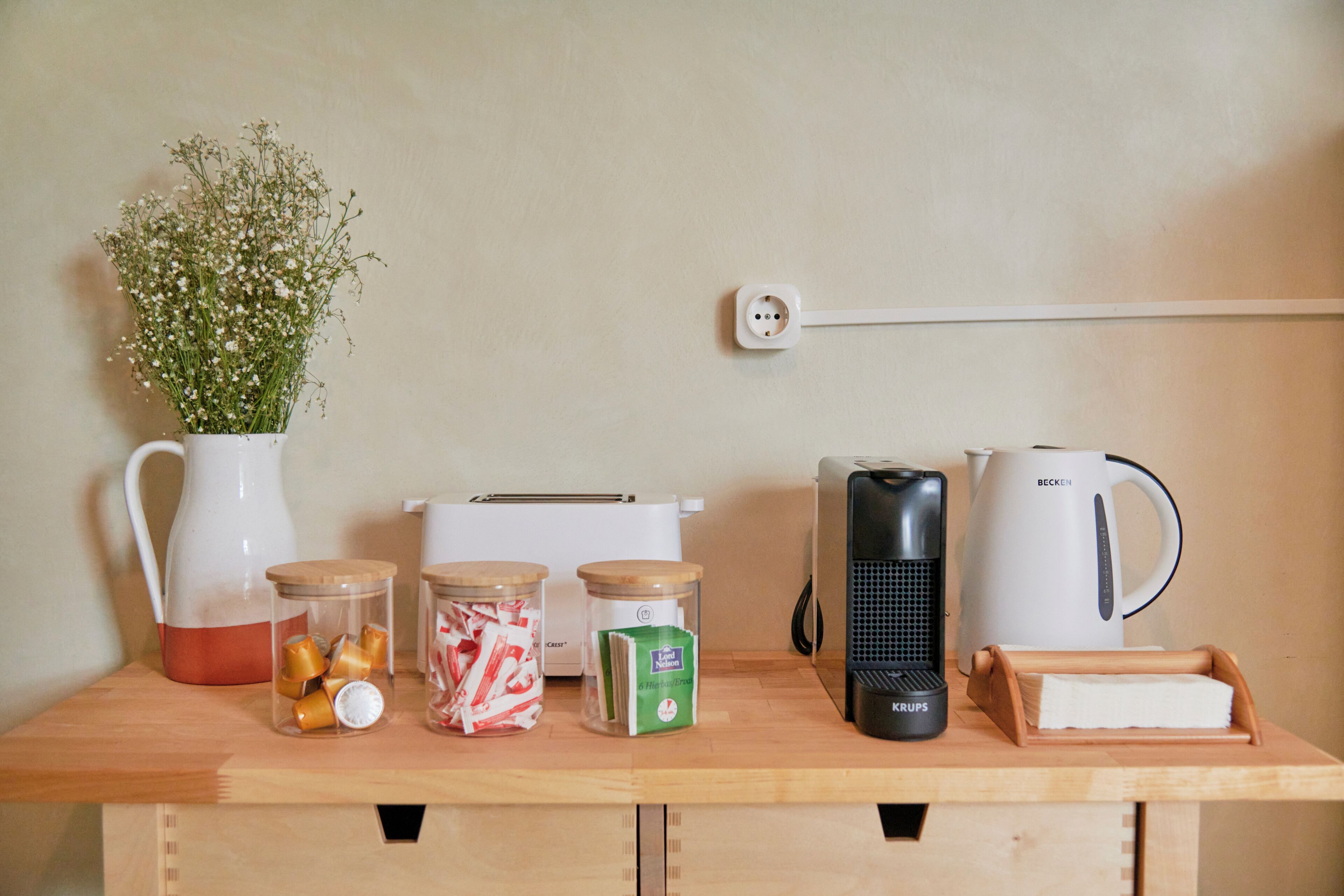 A kitchen counter with a coffee maker, toaster, kettle, and jars of food items.