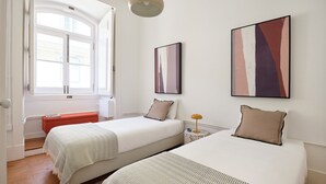 Een kamer met twee bedden, een raam en kunstwerken aan de wanden.
