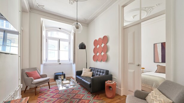 Een woonkamer met een bank, fauteuils, een salontafel en een vloerkleed met een patroon.
