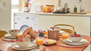 Een ontbijttafel met verschillende soorten eten, een wasmachine en een gootsteen op de achtergrond.