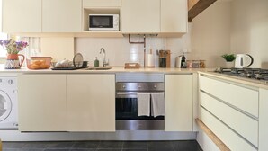 Een kleine keuken met een ingebouwde oven, magnetron en vaatwasser.