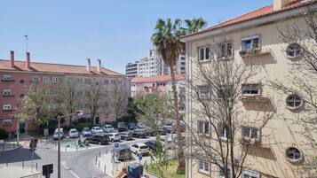 Una calle residencial con coches estacionados, una palmera y edificios de varios pisos.
