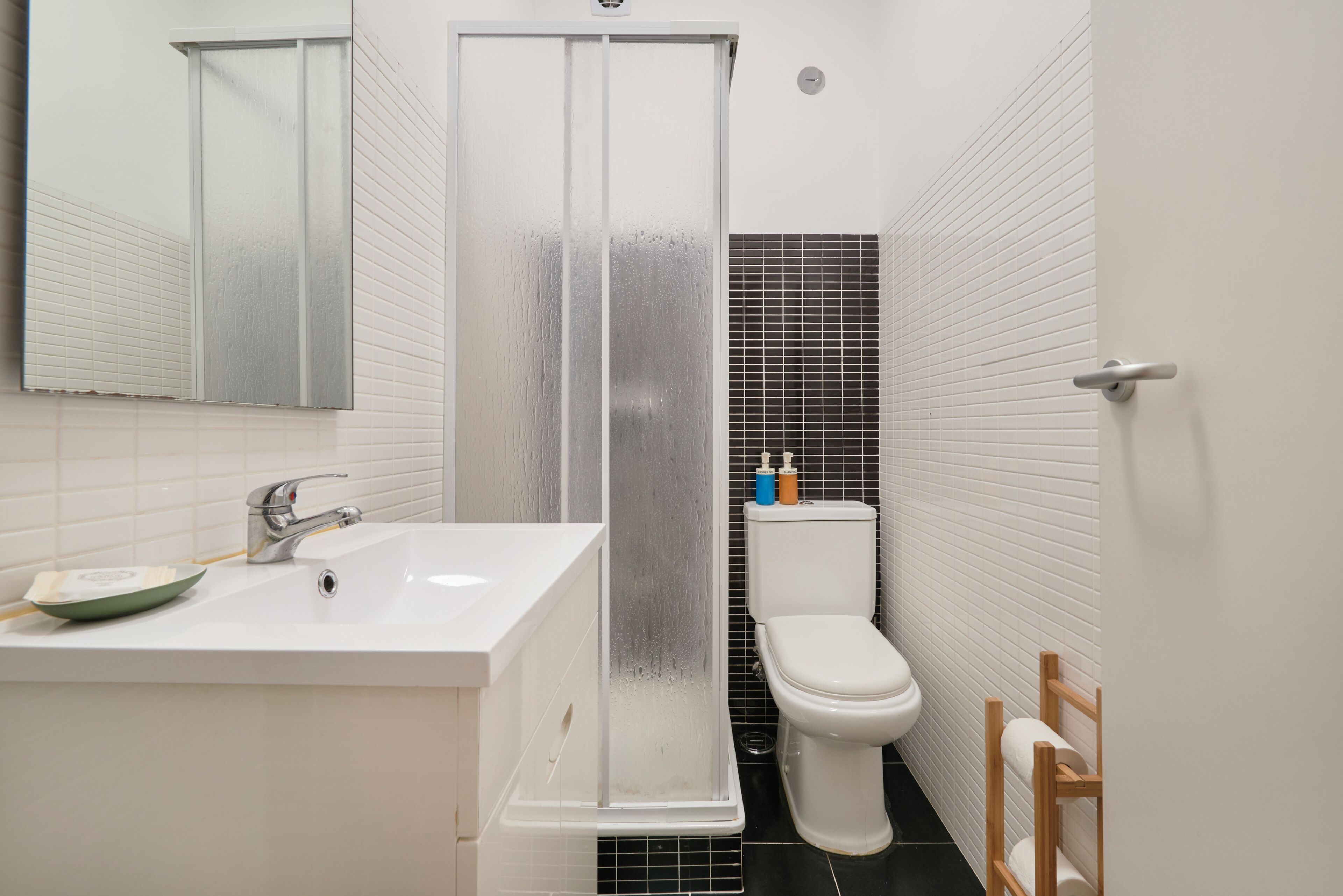 Een badkamer met een witte wastafel, toilet, douchecabine en spiegel.