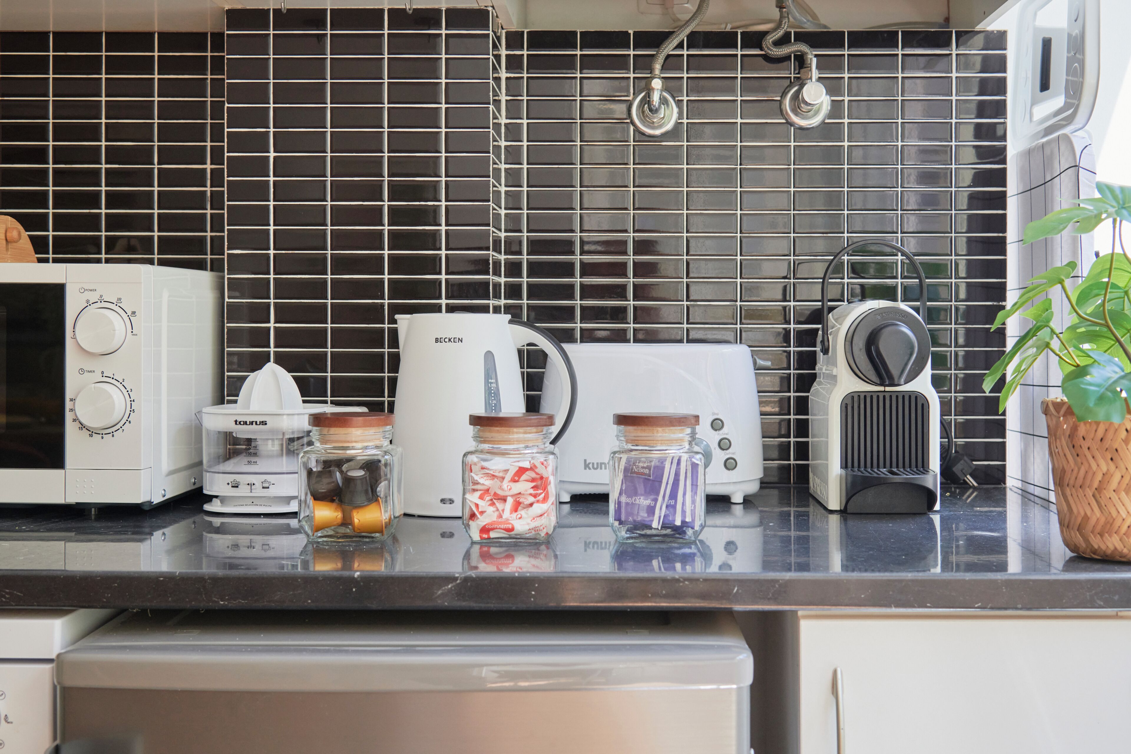 A kitchen with a microwave, toaster, kettle, and a coffee maker on the counter.