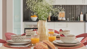 Ein Frühstückstisch mit Blumen, Schüsseln, Orangensaftgläsern und Gebäck.