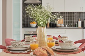 A breakfast setting with a vase of flowers, bowls, glasses of orange juice, and pastries.