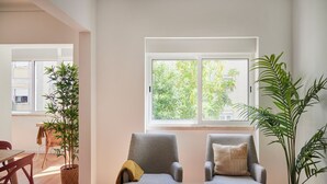 Ein Zimmer mit zwei Sesseln, einem Esstisch und Topfpflanzen.