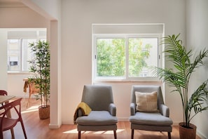A room with two armchairs, a dining table, and potted plants.