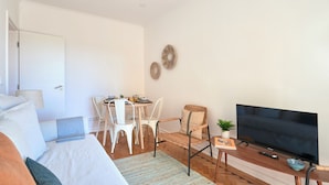 A modern room with a bed, a TV, a dining table with chairs, and a small side table with a plant. - Enjoy The Sunny Balcony, By Timecooler (Lisbon)