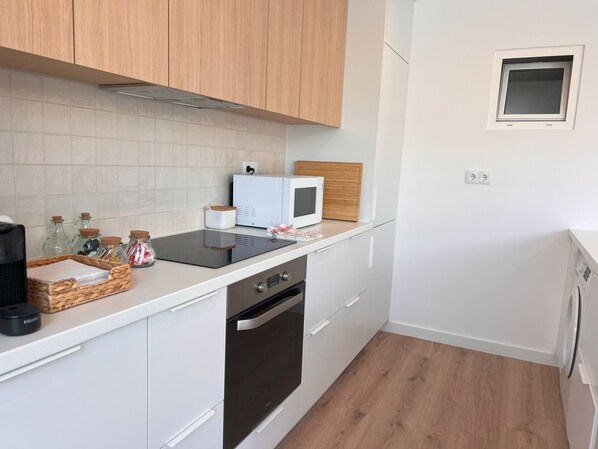 A compact kitchen with white cabinets, a microwave, a toaster, and a small window. - Central Beach Villa W Heated Pool, By Timecooler (Cascais)